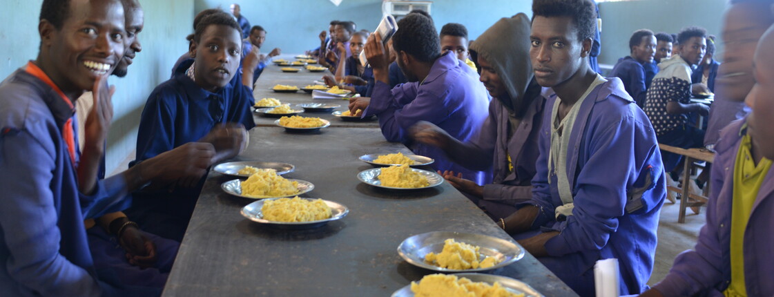 Internatsschüler beim Mittagessen Jugendliche in Schuluniformen sitzen in einer Kantine in Äthiopien an langen Tischen und nehmen gemeinsam eine Mahlzeit ein.