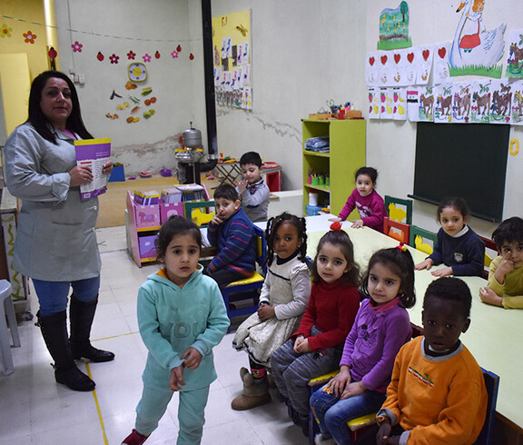 Eine Gruppe Kinder mit einer Betreuerin in einem Raum mit Spielzeug