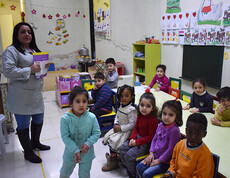 Eine Gruppe Kinder mit einer Betreuerin in einem Raum mit Spielzeug