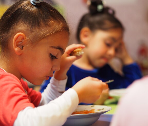 Zwei Kinder essen eine warme Gemüsesuppe.