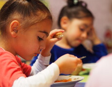 Zwei Kinder essen eine warme Gemüsesuppe.