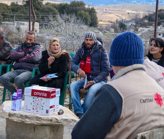 Caritas-Team diskutiert mit syrischen Landwirt*innen im Freien über Themen der Gemüseproduktion