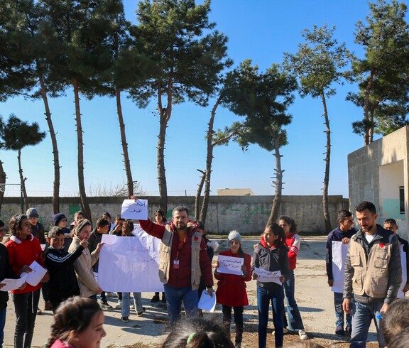 Caritas-Mitarbeitende mit Kindern bei einer Umwelt-Aktion im Freien in Tartous