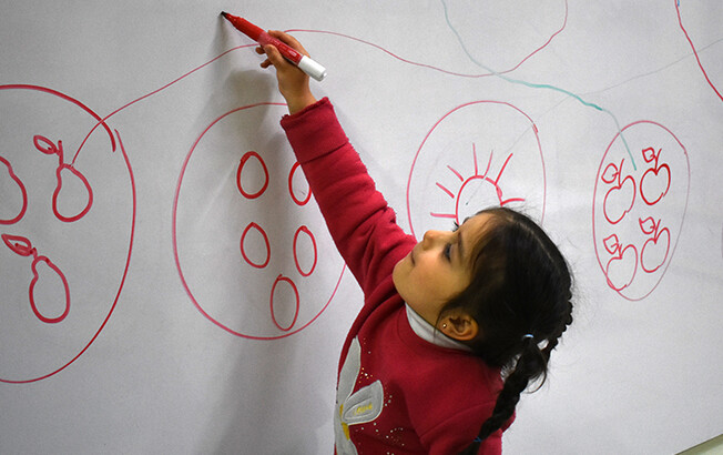 Ein Mädchen zeichnet an einer Tafel