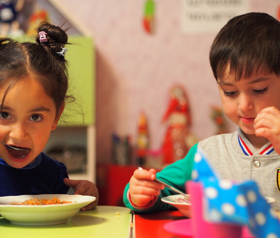Zwei Kindergartenkinder essen eine warme Gemüsesuppe