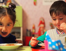 Zwei Kindergartenkinder essen eine warme Gemüsesuppe