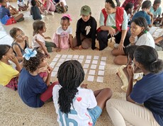 Kinder sitzen in Gruppen zusammen und spielen Spiele am Boden
