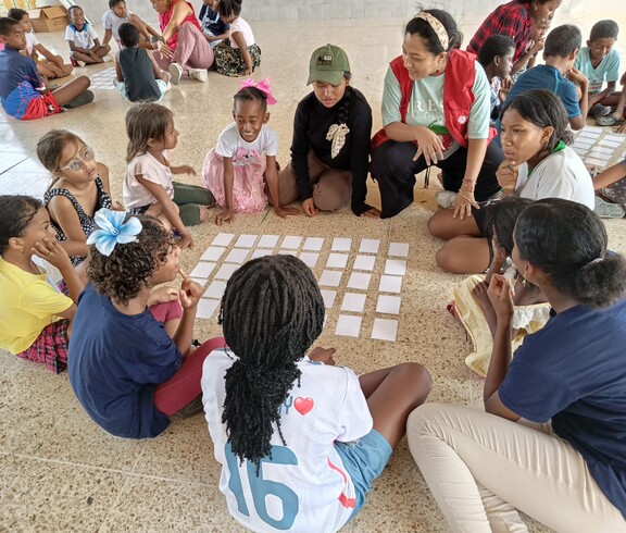 Kinder sitzen in Gruppen zusammen und spielen Spiele am Boden