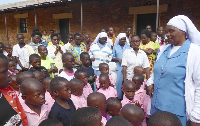 Eine Gruppe von Kindern und mehreren Schwestern und Erwachsenen steht gemeinsam im Freien vor einem Gebäude.