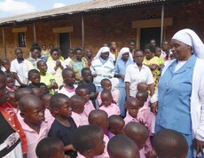 Eine Gruppe von Kindern und mehreren Schwestern und Erwachsenen steht gemeinsam im Freien vor einem Gebäude.
