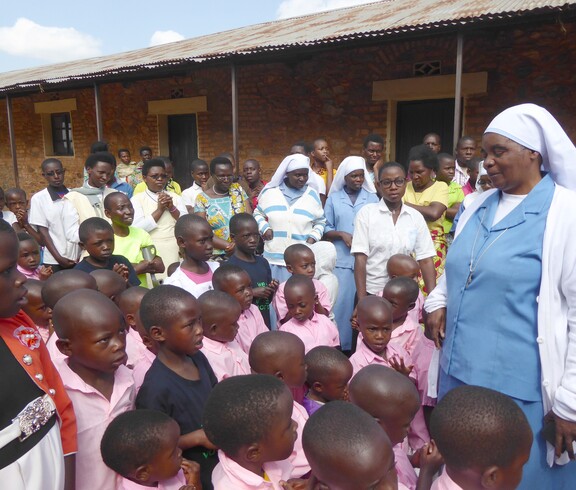 Eine Gruppe von Kindern und mehreren Schwestern und Erwachsenen steht gemeinsam im Freien vor einem Gebäude.