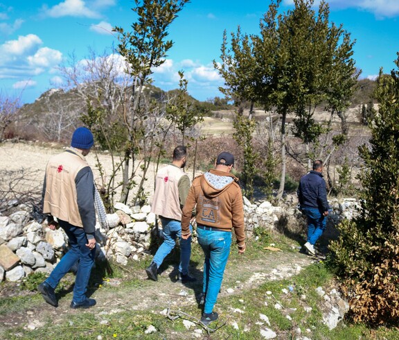 Caritas-Team und Landwirte laufen gemeinsam durch Felder zur Vorbereitung kommender Schulungseinheiten.