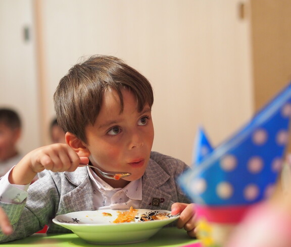 Portrait eines Jungen in einem Kindergarten, der eine Gemüsesuppe ist.