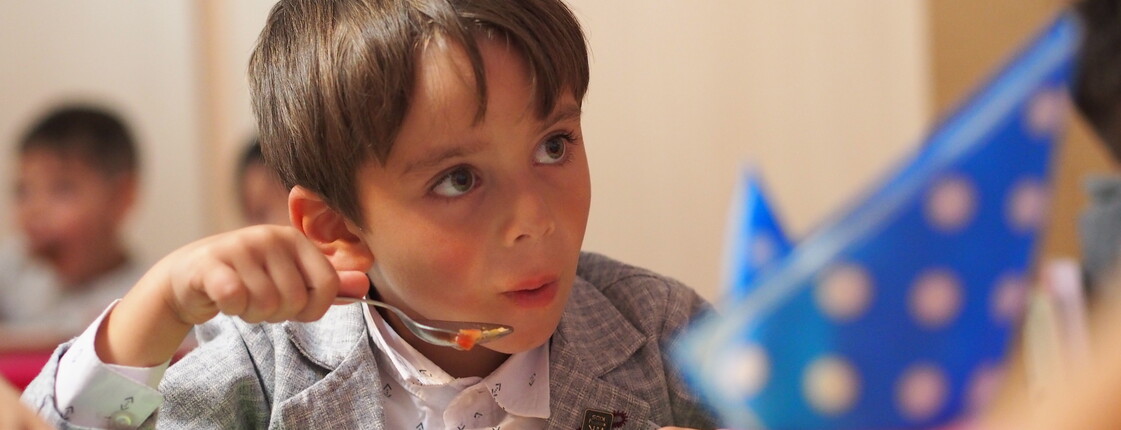 Portrait eines Jungen in einem Kindergarten, der eine Gemüsesuppe ist.